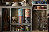 Collection of vintage cans and cooking utensils on simple, wooden kitchen shelves