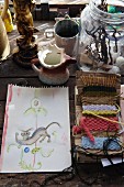 Drawing and weaving patterns surrounded by flea market collectors' items on rustic wooden table