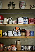 Collection of coffee cups, tea bowls and china jars on simple wooden shelves
