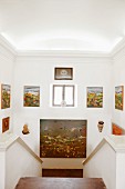 Sammlung verschiedener Gemälde an den Wänden eines gemauerten Treppenabgangs