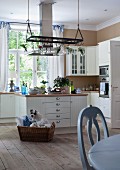 Pale country-house kitchen with island counter, untreated wooden floor and pale blue dining table