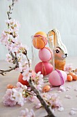 Easter arrangement of dyed eggs, chocolate rabbit & sprig of cherry blossom