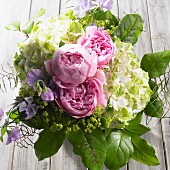 Bouquet of peonies, hydrangeas, sweet peas and lady's mantle on wooden surface