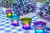 Blue still life arrangement with Hydrangea flowers and colourful lit tea lights