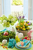 Table set for Easter with spring flowers, china rabbits and Easter place setting