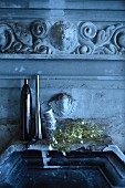 Steinbecken mit verspiegelten Vasen, Tassen und Weihnachtsdeko, darüber antik griechische Stuckelementen
