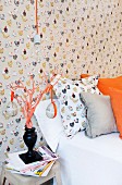 Hen-patterned wallpaper and pillow behind Easter eggs hanging from orange ribbons