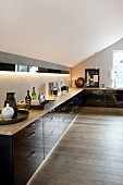 Black, glossy, fitted corner kitchen in attic apartment with country-house board floor