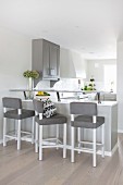Breakfast bar with upholstered stools in white and grey, open-plan kitchen