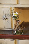 Delicate natural arrangement with hellebore on farmhouse dresser