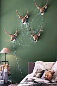Antlers and fairy lights on green bedroom wall