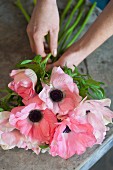 Female hands putting together a bouquet of pale pink anemones