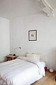 Minimalistisches Schlafzimmer mit weißer Bettwäsche und Wandbild