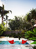 Pool mit zwei roten Butterfly Chairs hinter Glasbrüstung