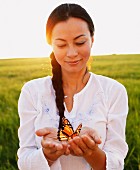 Woman holding butterfly in cupped hands