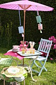 Glasses and carafe on garden table with Oriental parasol and party decorations