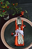 Place setting with linen napkin, ribbon napkin ring, decorative fly agaric mushrooms and rosehips