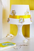 Flower-shapes cut from map and golden ribbon decorating lampshade