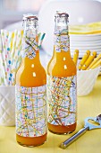 Flaschen mit Party Deko - Banderole und ausgestanzte Blütenformen aus alten Stadtplänen