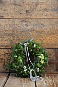 Romantic Christmas wreath of mistletoe and Star-of-Bethlehem flowers leaning against wooden wall