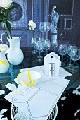 Wedding symbols; paper house model, broken crockery stuck together with yellow tape, stemware and vases on glass table