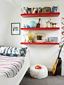 Red floating shelves, white sleigh bed, pouffe and guitar in cheerful teenager's bedroom