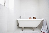 Zwei kleine Mädchen lugen über den Rand einer Retro Badewanne