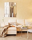 Fur blanket on ottoman and elegant sofa below pendant lamp with mirrored lampshade