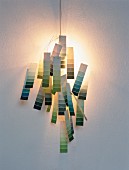 Hand-crafted sconce lamp made from paint colour charts threaded on wire