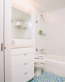 Washstand with large drawers and blue-green mosaic floor tiles in white bathroom