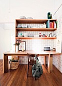 Wooden table under shelves with dishes on wooden floor