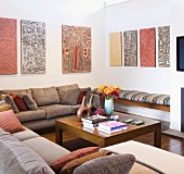 Aboriginal artworks above seating area with comfortable sofas and simple, exotic-wood coffee table