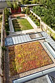 View of property; view down onto green roof with skylights and garden with small trees and lawn