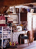 Überfüllte, kleine Nähwerkstatt mit antiken Möbeln, Dekowaren und Stapeln handgefertigter Kissen aus historischen Stoffen