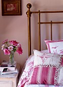 Scatter cushions with deep pink Toile de Jouy patterns on brass bed