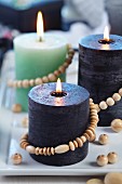 Various candles decorated with strings of wooden beads