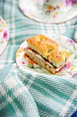 Tomato and mozzarella focaccia sandwich on floral plate and white and blue checked woollen blanket
