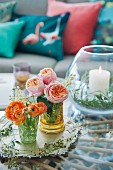 Australian Christmas arrangement of Ranunculus and roses in ornate glasses and candle lantern on tray on coffee table