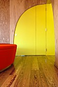 Modern, curved, yellow interior door in wooden wall of foyer
