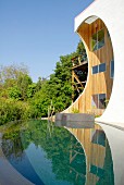 Unusual wooden house with apertures in protruding front facade, infinity pool and wild garden