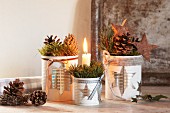 Christmas arrangement with lit candle in tin can with star motif