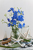 Bouquet of larkspur and candle lantern decorated with beachcombing finds