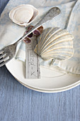 Place settings with silver fork, seashells and name tag