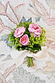 Small bridal bouquet of lady's mantle and roses on patterned surface