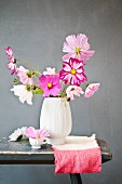 Bisque vase of cosmos on dip-dyed cloth against grey background