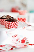 Chocolate muffins in red and white paper cases on white tabletop