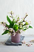 Flowering twigs and lily of the valley in pink glass vase