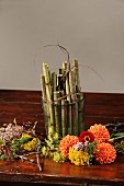 Autumn flowers and glass vase of knotweed stems on table