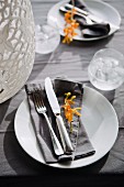 Two place settings with cutlery and yellow flowers on grey linen napkins