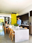 Küchentheke und tiefer gesetzter Essplatz aus Marmorplatten mit finnischen Stuhlklassikern in offener Küche
